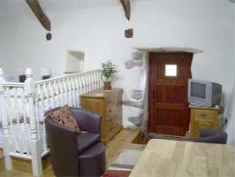 Living/dining area with raised twin bedded part to the left .    Beudy Bach